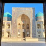 Madrasa storica con cupole turchesi vista attraverso un portale monumentale in Uzbekistan